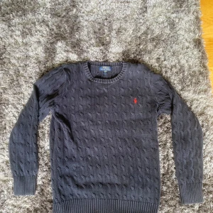 Mörkgrå stickad tröja från Polo Ralph Lauren - Säljer en mörkgrå stickad tröja från Polo Ralph Lauren med rund halsringning. Mycket bra skick o h storlek (18-20) men sitter som en S.