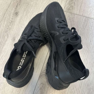 Svarta Nike React Infinity  - Snygga helsvarta Nike React Infinity sneakers med stickad ovandel och tjock, dämpad sula. Skorna har snörning och diskret Nike-logga på sidan. Är i väldigt bra skick. 