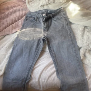 Flared Gråa jeansbyxor från Gina Tricot - Säljer ett par gråa  jeansbyxor från Gina Tricot med klassisk femficksdesign och flared ben. Byxorna har normal passform, dragkedja och knapp framtill samt bälteshällor i midjan. Perfekta för en avslappnad och stilren look.