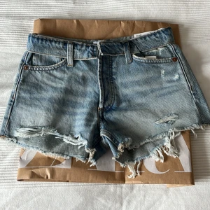 Zara ljusblå lågmidjade jeansshorts  - Ljusblå lågmidjade jeansshorts från Zara med fransiga kanter och slitna detaljer. Skitsnygga jeansshorts med knappgylf och bälteshällor. Helt nya och aldrig använda(endast testade), säljer pågrund av att dom var för små tyvärr. Kontakta mig vid frågor eller funderingar😊       Midjemått rakt över: 35cm                                      Längd: 25cm