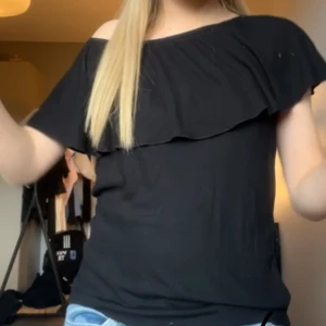 Svart topp med volang  - Supersnygg svart topp med volang! Perfekt till sommaren. Kan användas och stylas på olika sätt. Jätte fin och mjukt små ribbat material! Storlek xs men är bra till S.