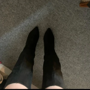 Svarta höga stövlar med klack - Säljer ett par svarta höga stövlar med klack. Skorna är i mocka och har en stilren design som passar perfekt till många outfits. De går upp tillknäet och har en stadig blockklack.