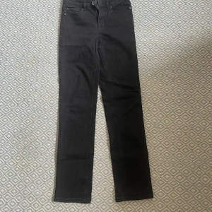 Svarta raka jeans - Snygga svarta jeans med klassiska  raka ben. Byxorna har normal passform och stängs med dragkedja och knapp. Perfekta till många olika outfits och enkla att matcha med andra plagg.