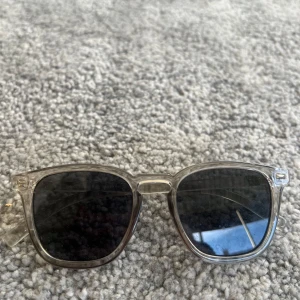 Transparenta solglasögon med svarta glas - Snygga solglasögon med transparent båge och svarta glas. Klassisk fyrkantig form som passar de flesta ansikten. Perfekta för soliga dagar och ger en stilren look.