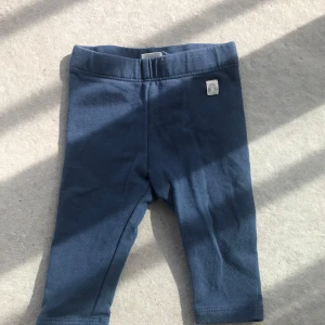 Blå leggings med resårmidja - Mörkblå leggings i mjuk bomull med resår i midjan. Enkla och stilrena med en liten vit etikett med regnbågsmotiv på höften. Perfekta för en avslappnad och bekväm stil.