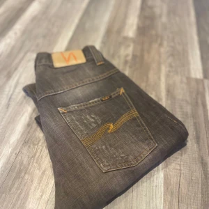 Mörkgrå jeans från Nudie Jeans - Säljer ett par mörkgrå jeans från Nudie Jeans med klassisk femficksdesign och kontrastsömmar i gult. W29 L32.    Flertal mer jeans i profilen 