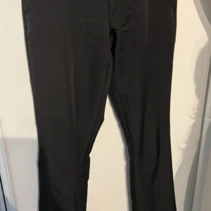 Svarta kostymbyxor från BikBok - Klassiska svarta kostymbyxor från BikBok med rak passform och normal midja. Byxorna har enkel design utan synliga detaljer och passar perfekt till en stilren look. Materialet känns mjukt och följsamt.