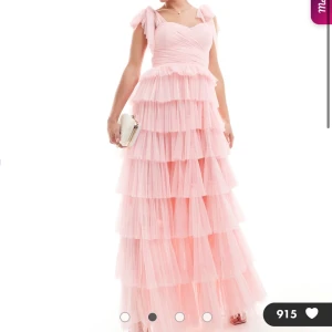 Långklänning i tyll med volanger och rosett - Drömmig långklänning i tyll med flera lager volanger och rosett på axlarna. Såå fin men hittade en annan jag gillade bättre, aldrig använd🩷Klänningen är rosa så de är den på första bilden men då klänningen inte längre finns på hemsidan i rosa så la jag in bild på en likadan fast svart bara för att visa från olika håll!! Nypris 1 700kr 