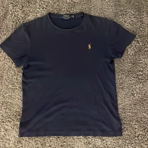 Mörkblå Ralph Lauren T-shirt - Säljer nu denna mörkblåa Ralph lauren t shirten då jag inte hittat användning för den och därför har den hängt i garderoben. Den är använd ett fåtal gånger och är handtagen väl