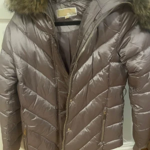 guld rosa  dunjacka med fuskpäls från Michael Kors - Säljer en guld rosa  pufferjacka från Michael kors helt ny använd ungefär 1 gång köpt i vintras.