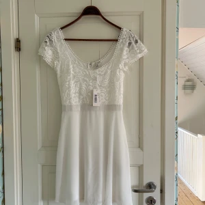 Oanvänd vit spetsklänning Nelly, 38 - Oanvänd med prislapp. Perfekt till student, skolavslutning mm! Nypris 499 kr. Storlek 38. Slutsåld på Nelly, länk till klänningen för mer bilder: https://nelly.com/se/produkt/nelly-wishes-come-true-dress_190675-0001/ 