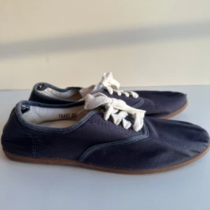 Marinblå snörskor strl 39 - Sköna marinblå seglarskor / snörskor / sneakers från H&M med vita snören och stilren brun sula.   Är väldigt kompakta så perfekta att ha med på resan eller i handväskan på festen när du fått nog av klackarna.   Hämtas i Stockholm eller skickas mot porto.