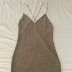 Guld glittrig kort klänning från H&M - Snygg guld glittrig klänning med korsade band i ryggen från H&M i strl s