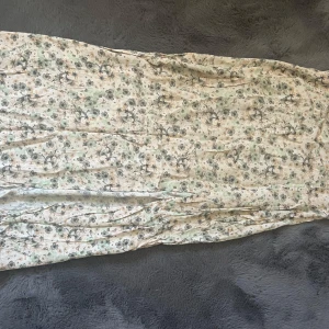 Lång kjol - Din kjol med massa blommor på, den har en slits så den är enkel att gå med. Den ser lite ”skräpig” ut men skulle rekommendera att stryka den men jag har tyvärr inte tillgång till det här, inge defekter