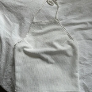 Halterneck topp vit - Säljer vit halterneck topp från Bik Bok. Aldrig använd. Har ett justerbart snöre som man knyter toppen med. Normal i storleken.