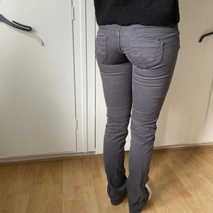 Grå straight jeans från Pepe Jeans - Säljer ett par gråa straight fit jeans från Pepe Jeans med låg midja och dubbla knappar framtill. Jeansen har klassiska fickor både fram och bak samt snygga sömdetaljer. Perfekta för en stilren och avslappnad look. Storlek W26/L34💗💗
