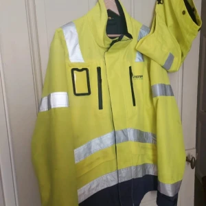 Gul varseljacka från Blåkläder - Varseljacka i gul färg från Blåkläder med reflexdetaljer och svarta partier nertill. Jackan har hög krage, dragkedja framtill, flera fickor och logga på bröstet samt ryggen. Perfekt för utomhusarbete och synlighet.