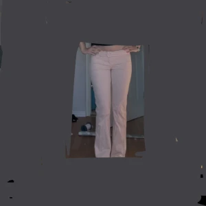 Ljusrosa bootcut byxor - Säljer ett par ljusrosa byxor med bootcut passform och normal midja. Men går att vika ner dem så de blir low waist så som jag har på bilden! Byxorna har klassiska fickor både fram och bak samt stängs med dragkedja och knapp. Perfekta för dig som vill ha en stilren och enkel look. Skriv vid frågor! Jag brukar ha strl S 🥰