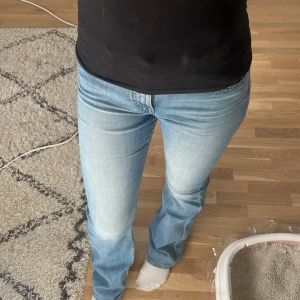 Ljusblå bootcut jeans - Säljer ett par ljusblå jeans med bootcut-modell och klassisk femficksdesign. Jeansen har normal passform och är tillverkade i denim med lätt tvättad look. Perfekta för dig som gillar en tidlös stil med lite utsvängda ben.