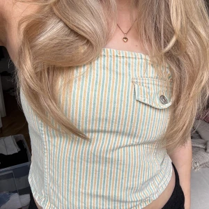 Randig jeans-korsettopp - Säljer en snygg randig korsettopp i pastellfärger med knappar bak!