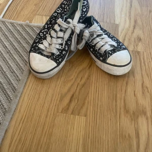Svarta sneakers med leopardmönster - Svarta sneakers med gråvitt leopardmönster och vita snören. 