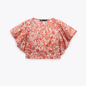 Blommig croppad blus i orange och vitt - Säljer en blommig croppad blus i orange och vitt med vida korta ärmar