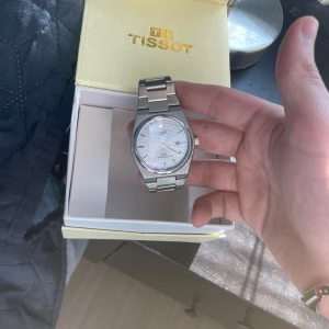 Tissot PRX Powermatic 80 herrklocka i silver - Säljer en stilren Tissot PRX Powermatic 80 med silverfärgad länk och boett i rostfritt stål. Urtavlan är ljus med rutmönster och datumvisning. Klassisk design med tydliga index och automatisk rörelse. Perfekt accessoar för dig som gillar tidlös stil. Pris går självklart att diskutera, även byten. Extra länkar igår såklart 