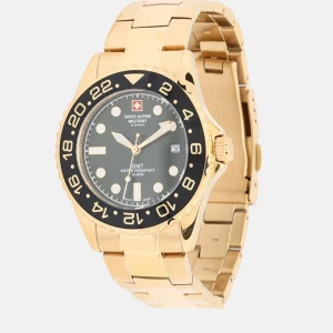 Guldfärgad klocka från Swiss Alpine Military - Stilren herrklocka i guldfärgat metallarmband och svart urtavla. Klockan har tydliga siffror, datumvisning och vridbar bezel. Levereras i originalask med Swiss Alpine-logga.