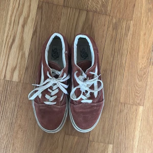 Vinröda Vans Old Skool sneakers - Säljer ett par klassiska Vans Old Skool sneakers i vinröd mocka med vita detaljer och vit sula. Skorna har vit snörning och den ikoniska sidoremsan. Perfekta för en avslappnad och stilren look.