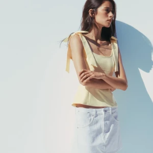 Ljusgul topp med rosettband - Säljer denna slutsålda ljusgul topp med breda axelband som knyts i rosetter från zara!Toppen har fyrkantig ringning och är perfekt för varma dagar. Liten i storlek sitter mer som en M. 