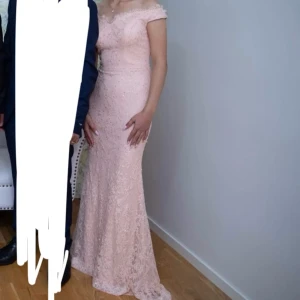 Balklänning - Elegant långklänning i champagnefärg med offshoulder-skärning, spetsdetaljer och glittriga inslag. Perfekt för bal eller festliga tillfällen.