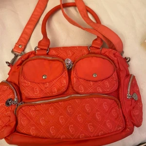  axelväska  - Säljer en  axelväska med quiltat mönster och silverfärgade detaljer. Väskan har flera ytterfack med dragkedja och tryckknapp samt ett rymligt innerfack med mönstrat foder. Perfekt för dig som vill ha plats för allt du behöver.