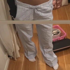 Blåvitrandiga byxor  - Säljer ett par blåvitrandiga mjukisbyxor med resår i midjan. Byxorna har en loose passform och raka ben, perfekta för en avslappnad stil. Tunt och mjukt material som känns skönt mot huden.