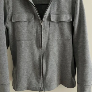 Grå Overshirt  - Säljer en grå stilren overshirt som är i väldigt bra skick säljer den för att den inte passar mig i storleken [Storlek M] priset kan diskuteras vid snabb affär 
