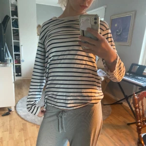 Randig långärmad tröja - Säljer en vit långärmad tröja med svarta horisontella ränder.Tröjan har en avslappnad passform och rund halsringning. Perfekt för en chill och stilren look.