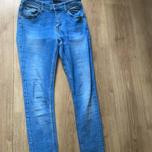 Blå jeans från Tiger of Sweden - Säljer ett par klassiska blå skinny jeans från Tiger of Sweden. Jeansen har fem fickor, dragkedja och knapp framtill samt snygga detaljer med märkets logga. 