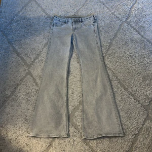 Ljusgrå bootcut jeans från Divided H&M - Säljer ett par ljusgrå bootcut jeans från Divided H&M. Jeansen har klassisk femficksdesign, normal passform upptill och utsvängda ben. Perfekta för dig som gillar en retroinspirerad look.