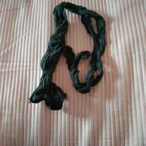 Svart tunn halsduk - En enkel och tunn mörkgrön halsduk i ett lätt material. Perfekt att slänga runt halsen för en chill look. Halsduken är smal och har en skrynklig struktur som ger en avslappnad vibe.