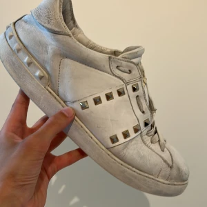 Valentino Rockstud - Snygga vita Valentino Rockstud sneakers i skinn med ikoniska nitar i guld längs sidorna. Klassisk rund tå, snörning och platt sula. Perfekt för dig som vill sticka ut med exklusiva detaljer och streetstyle-vibe. Självklart så är skorna äkta och priset är inte hugget i sten. Om du har några funderingar är det bara att skriva ✍️.