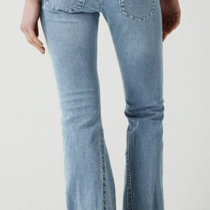 Ljusblå bootcut jeans från true religon - intressekoll på  ett par ljusblå bootcut jeans med klassiska bakfickor och snygg tvätt. Jeansen har en lätt utsvängd passform nertill och är perfekta för en avslappnad men trendig look. Eftersom det är ljusa jeans så har dem töjt sig lite är normalt strl 27 men skulle säga att dem nu passar både 27 och 28.