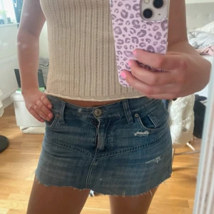 Blå jeanskjol  - Snygg blå jeanskjol med rå, fransig kant och slitna detaljer. Klassisk femficksmodell med dragkedja och knapp framtill. Perfekt för dig som gillar en avslappnad och trendig stil.