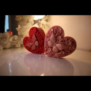 Butterfly Heart Candles - A stunning pair of heart-shaped candles, intricately carved with floral patterns and a raised butterfly design. Comes in soft pink and deep red tones, perfect for romantic gifts, Valentine's Day, or as elegant décor for weddings and special occasions. H:10.5cm B:11cm Depth:3.3cm