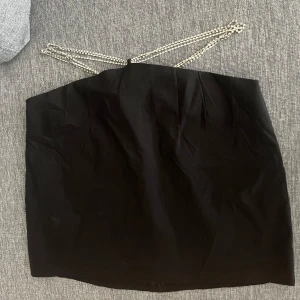 Svart kjol med stridsvagns - Super snygg fest kjol som tyvärr aldrig kommit till användning. Kjolen är högre i mitten av magen och svanken än vid höfterna. Över höfterna går strass band