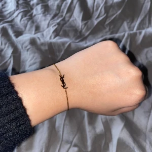 YSL armband - Superfint och stilrent armband från Saint Laurent med YSL-loggan i guld. Tunn kedja och minimalistisk design som känns lyxig och trendig. Kan användas vardagligt eller festligt. Nypris för den är ca 3900kr