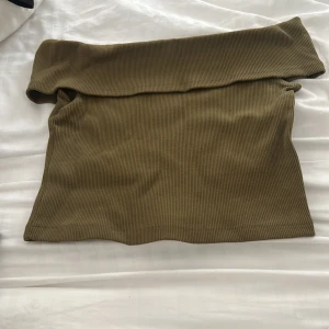 Olivgrön ribbad offshoulder tubtopp - Snygg olivgrön tubtopp med ribbad struktur och offshoulder-design. Toppen är croppad och sitter tight.