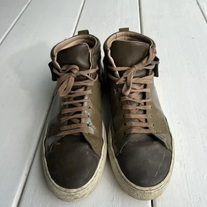 Olivgröna sneakers från ARIGATO - Ollivgröna high-top sneakers från ARIGATO med glansig finish och bruna detaljer. Skorna har bruna snören, beige insida och vit sula. Pris kan diskuteras.