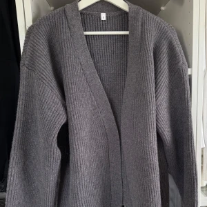 Grå ribbstickad kofta med bälte - Mysig grå ribbstickad kofta i storlek S från HM med breda ärmar och knytskärp i midjan. Koftan har en öppen front. Helt ny.