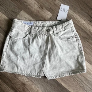 Vit jeanskjol från Zara XS - Vit, kort jeanskjol från Zara. Väldigt fin med en slits. Perfekt för en fräsch och stilren look. Har lappen kvar, helt oanvänd, endast testad.