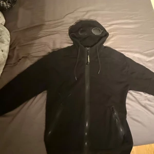 Svart gogglejacka från C.P. Company - Säljer min C.P. Company kofta i storlek M. Sällan använd och båda glasögonen finns kvar. Inga hål eller liknande. Kan mötas lite runt om stockholm. Nypris 2900 mitt pris 2000kr går att diskutera