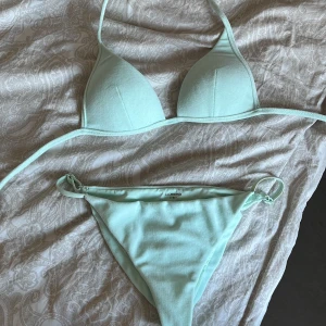 Calzedonia bikini - Snygg mintgrön bikini från Calzedonia med knytband på sidorna av trosorna och runt nacken. Perfekt för en dag på stranden eller vid poolen. Enkel och stilren design som ger en fräsch look.
